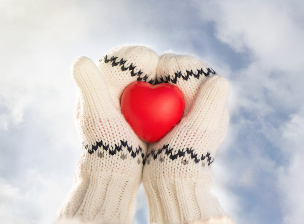 Photo showing two gloved hands holding a red heart